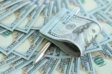 Golden pen clipping big amount of hundred dollar bills US banknotes