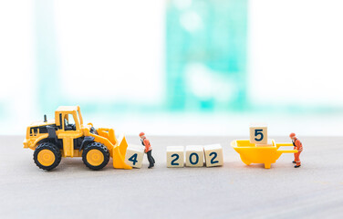 Good bye 2024 Happy New year 2025, miniature worker with wooden cube and front loader truck over blurred background, outdoor day light