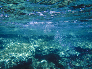 Dark blue ocean surface seen from underwater. Abstract waves underwater and rays of sunlight...