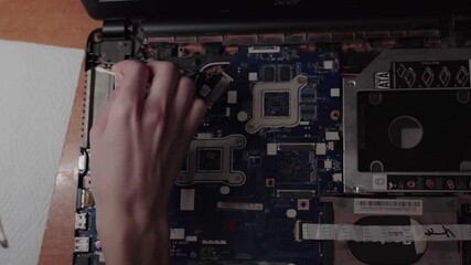 Man using tools repairing his laptop, high angle view. Professional technician working in computer service, flat lay. Checking and diagnosing the operation of the motherboard