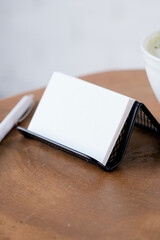 Fototapeta premium blank visit card mockup on white coffee table with green matcha tea near window