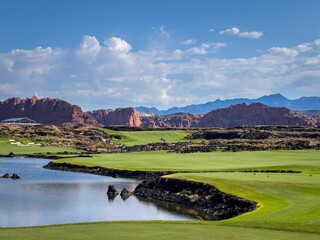 Golf course with red rock mountains and lake.