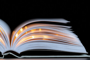 Open book with glowing pages on a dark background