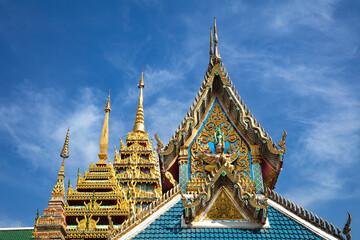 Decorative façade and rooftops, at the temple of Wat Khun Chan, Bangkok, Thailand. Blue sky and clouds in the background. 
