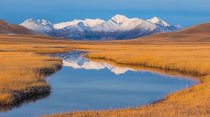 Naklejka premium A calm winding river reflects snow-capped mountains in a golden autumn steppe landscape.