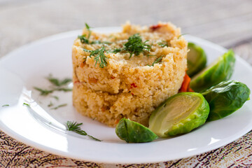 homemade cooked bulgur with Brussel sprouts in a plate, on a wooden table