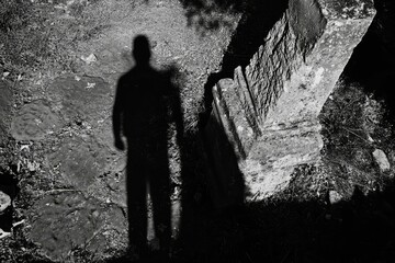 Shadowy figure near weathered stone monument.