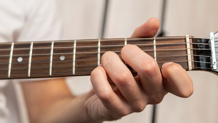 Guitar music. The performer plays. Practice chords. Male performer hands with fingers studying melody of song on electric string guitar fretboard indoors.