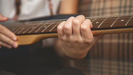 Close up. Girl playing electric guitar and practicing at home