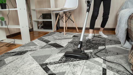 Low section of girl cleaning floor with vacuum cleaner at home