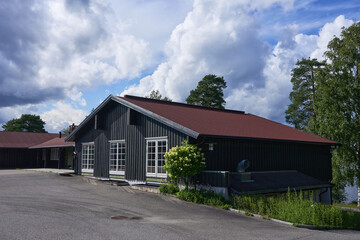 Obraz premium A charming Scandinavian cabin nestled within a lush, scenic landscape, perfect for tourism and connecting with nature. The peaceful setting invites relaxation and enjoyment of the outdoors