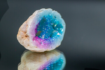 A natural electroplated agate crystal, beautifully polished and isolated in a studio, displays vibrant, iridescent hues with shimmering details