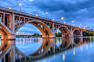 A bridge spans a river with a reflection of the lights on the water