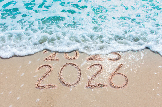 Message Year 2025 replaced by 2026 text written on beach sand background. Good bye 2025 - 2026 happy New Year coming concept. top view.