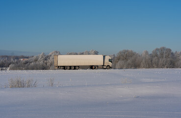 A big white truck drives on the highway in winter. Transport management. Logistics