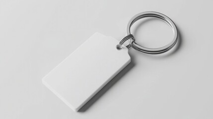 A close-up of a plain white keychain tag attached to a metal ring, displayed on a smooth grey background, showcasing its simple and minimalist design.