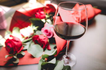 A glass of red wine paired with an elegant pink orchid flower arrangement on a wooden table, creating a cozy and sophisticated atmosphere.