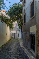Fototapeta premium The narrow alleys and old buildings of the Alfama neighborhood in Lisbon in the late afternoon