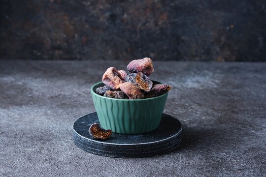 Dried dark figs in a green bowl on a green concrete background. Dried fruits. Ingredients for cooking. - Powered by Adobe