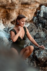 Woman Rocks Beach - Woman sitting on rocks by the sea in a swimsuit.
