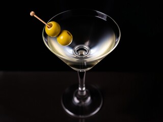 A close-up of a martini glass with two olives on a skewer.
