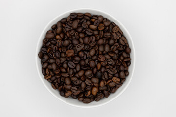 A top-down view of a white bowl filled with roasted coffee beans on a white background, showcasing their rich brown tones and smooth textures, ideal for coffee or food-related themes.