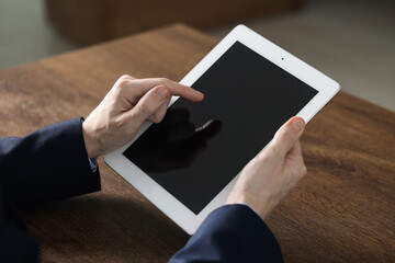 Businessman using tablet at wooden table, closeup. Modern technology