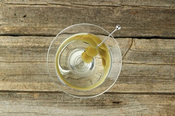 Martini cocktail with olives in glass on wooden table, top view