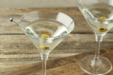 Martini cocktail with olives in glasses on wooden table, closeup