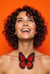 Woman smiling with red butterfly on her neck against orange background. Studio portrait. Health and thyroid awareness concept. Banner, poster with copy space. National Thyroid Awareness Month.