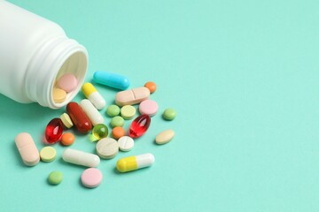 Various pills pouring out of medicine bottle on color background