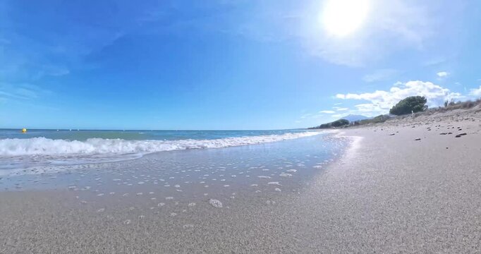 Waves crashing onto a sandy beach from a low ground perspective, highlighting natural coastal beauty