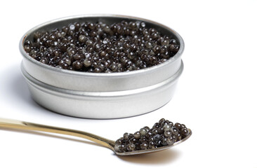 Black sturgeon caviar in gold spoon. Sturgeon caviar on a white background in a jar.