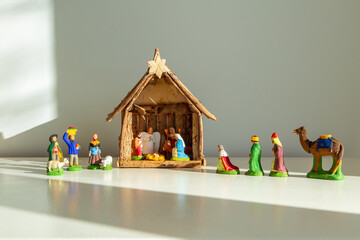 
Small traditional provencal painted clay nativity figurines set on plain cream background in ray of sunshine
