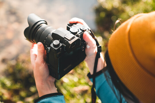 Outdoor photographer taking landscape photos using digital camera. Side view of man using dsrl outdoors in bright light