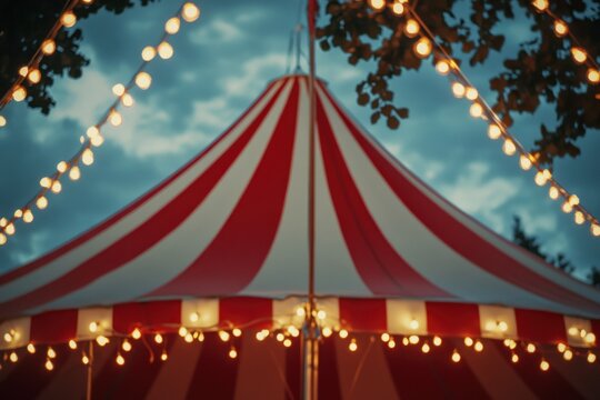 Colorful striped circus tent illuminated by warm glowing lights during twilight, capturing the enchanting atmosphere of festive outdoor events and gatherings