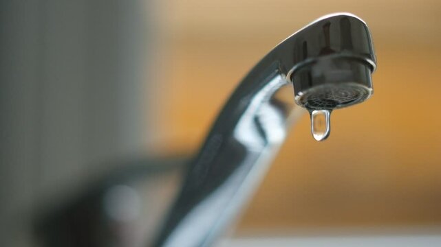 Robinet d'&eacute;vier qui fuit goutte par goutte, en gros plan, au ralenti.