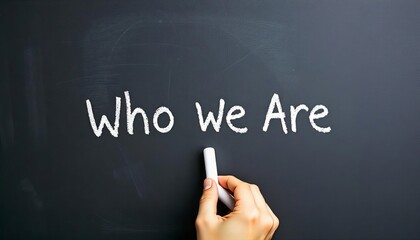 Hand holding white chalk writing "Who we are". Highlighting key business principles.