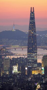 Impressive view of Seoul and Lotte World skyscraper at dusk, patrol helicopter flying low over city. Supertall skyscraper in its full height