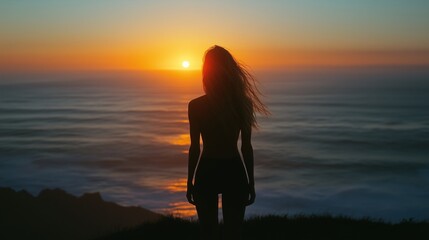 Fototapeta premium Silhouette of a Woman Watching a Breathtaking Ocean Sunset