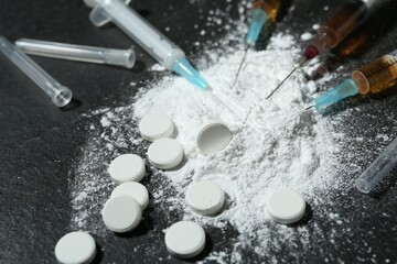 Drug addiction. Powder, pills and syringes on gray textured table, closeup
