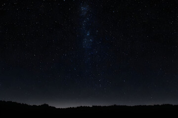 Majestic milky way illuminating night sky over dark forest