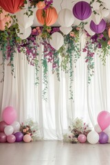 Obraz premium A beautifully decorated party space featuring colorful balloons, hanging lanterns, and vibrant floral arrangements against white drapes.