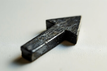 A black arrow-shaped object made of a solid material, possibly for decoration or guidance.