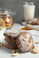 Tasty chocolate cookies with cashew and powdered sugar on white table, closeup