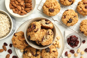 Delicious oatmeal cookies with raisins and nuts on white marble table, flat lay