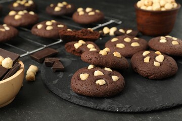 Tasty chocolate cookies with hazelnuts on black table, closeup