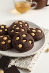 Tasty chocolate cookies with hazelnuts on white table, closeup