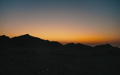 Rocky landscape in Al Ula, Early morning just before sunrise, crescent moon on orange sky