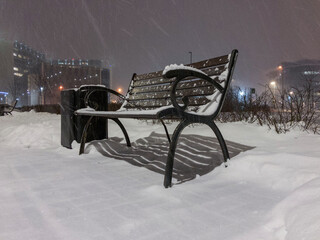 Cast iron bench standing in the park during snowfall.